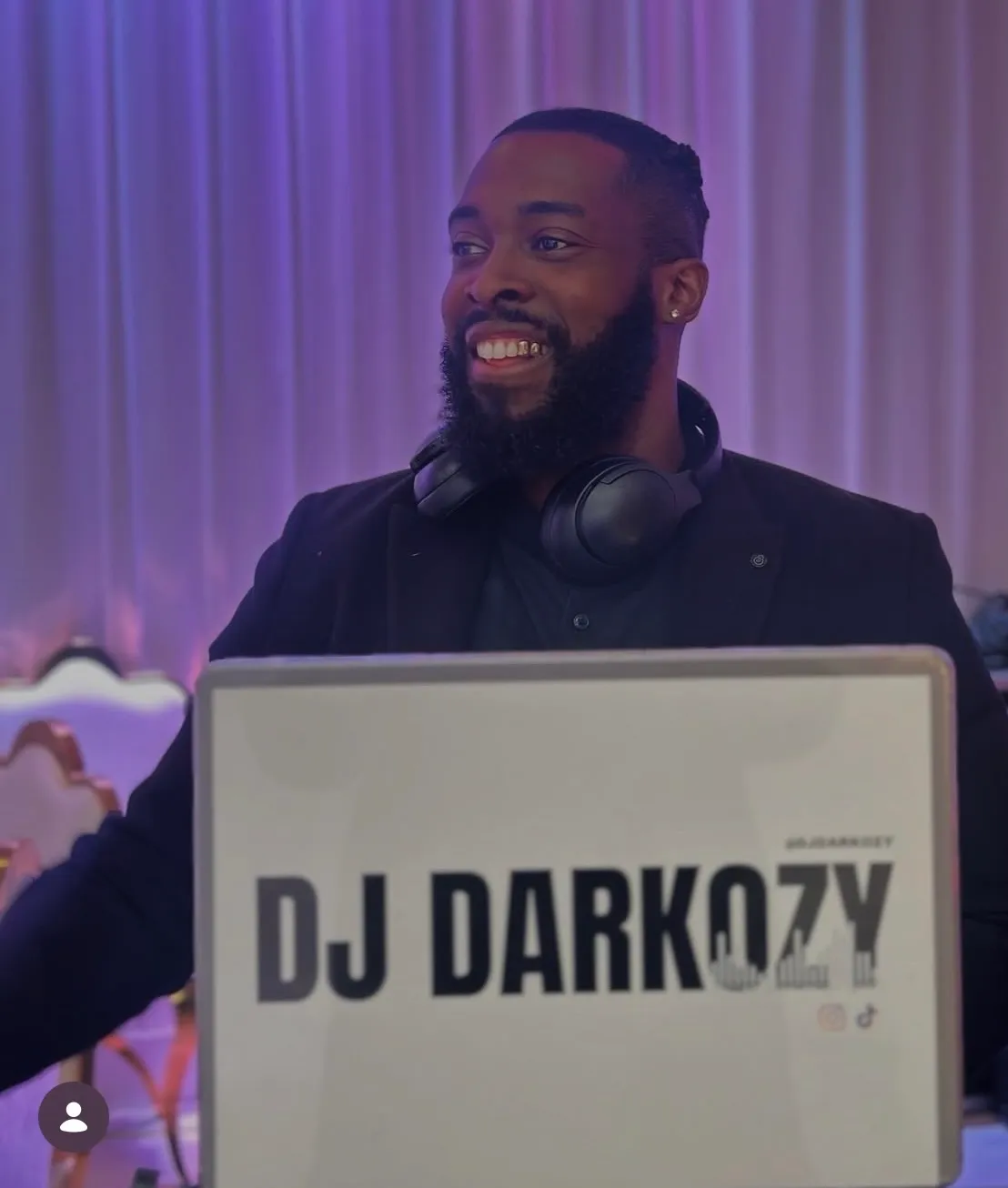 Richard Tandoh, DJ Darkozy, smiling behind his branded DJ booth at an event